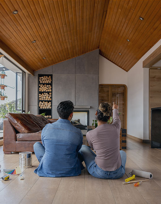 A couple sitting on the floor plan renovations to their living room.