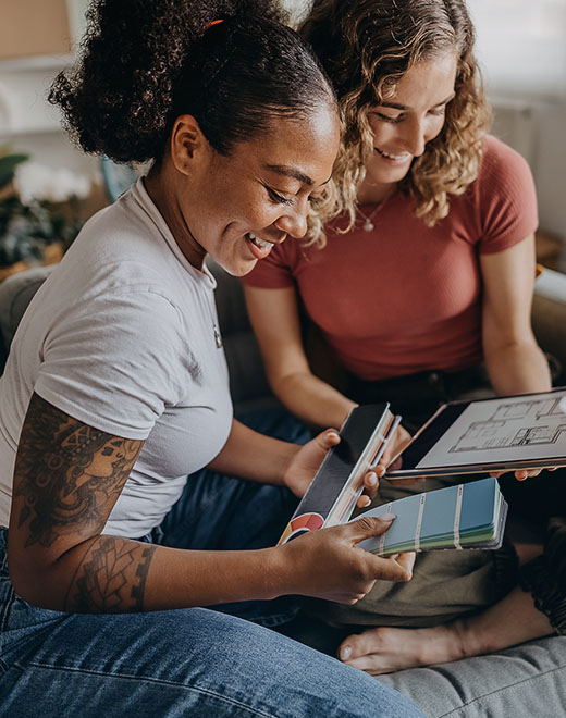 A couple smile together while browsing paint swatches.