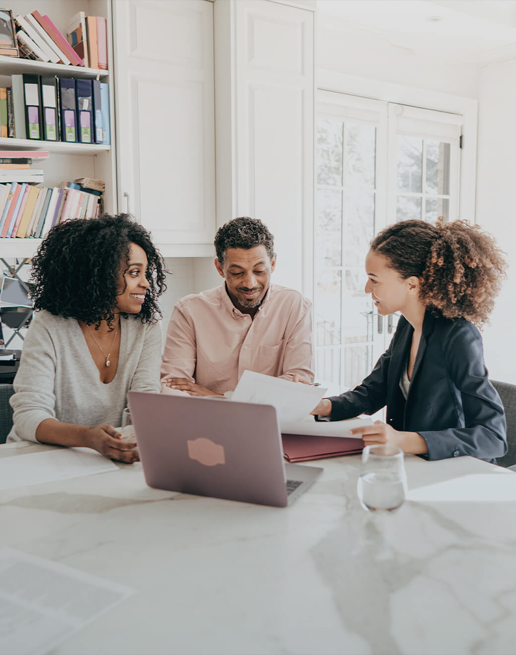 A couple with their real estate agent reviews paperwork.