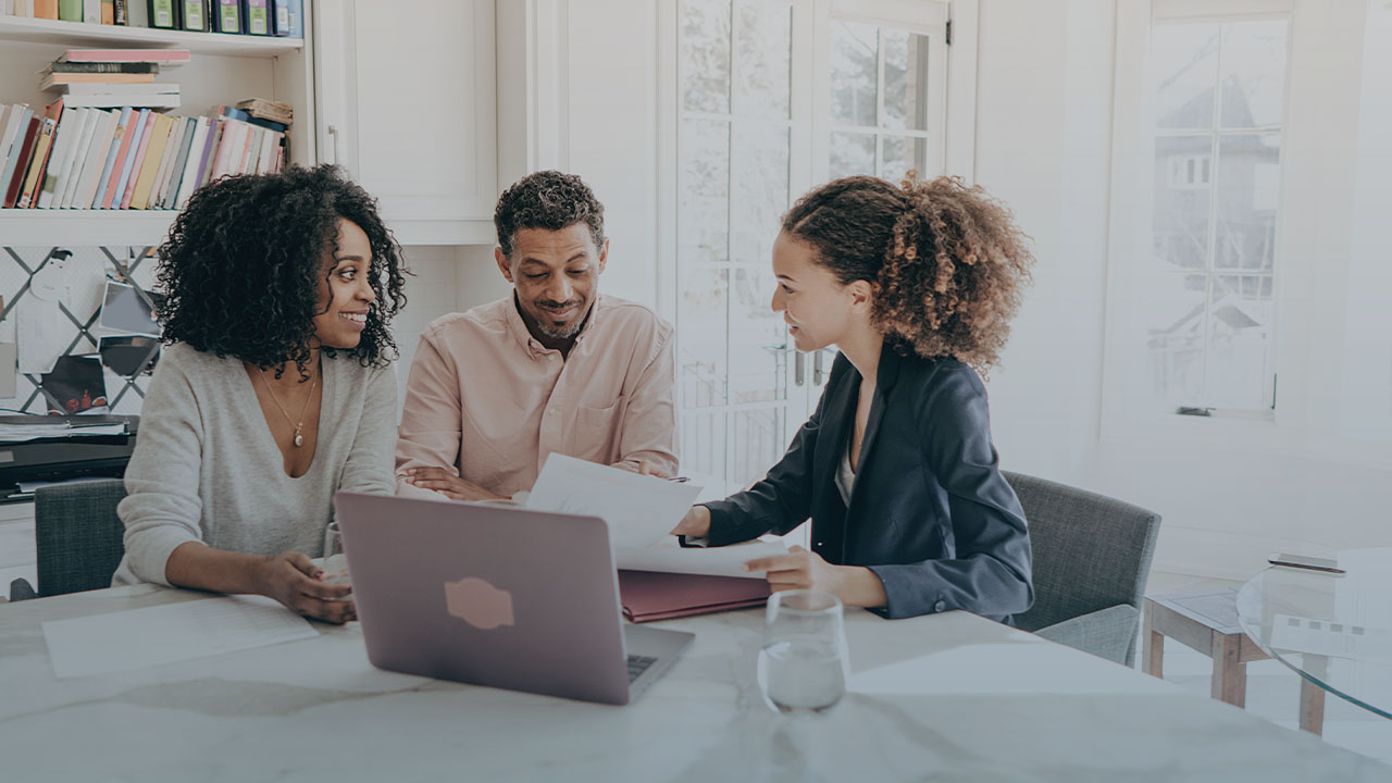 A couple with their real estate agent reviews paperwork.