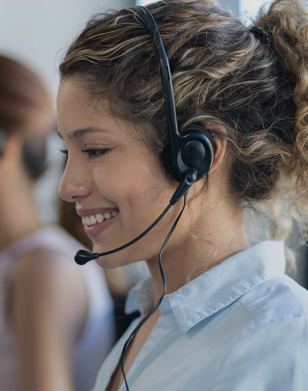 Young woman wearing a call headset and smiling.